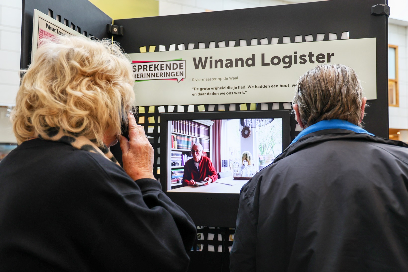 vrouw luistert naar een verhaal in de Mobiele Erfgoed Tentoonstelling
