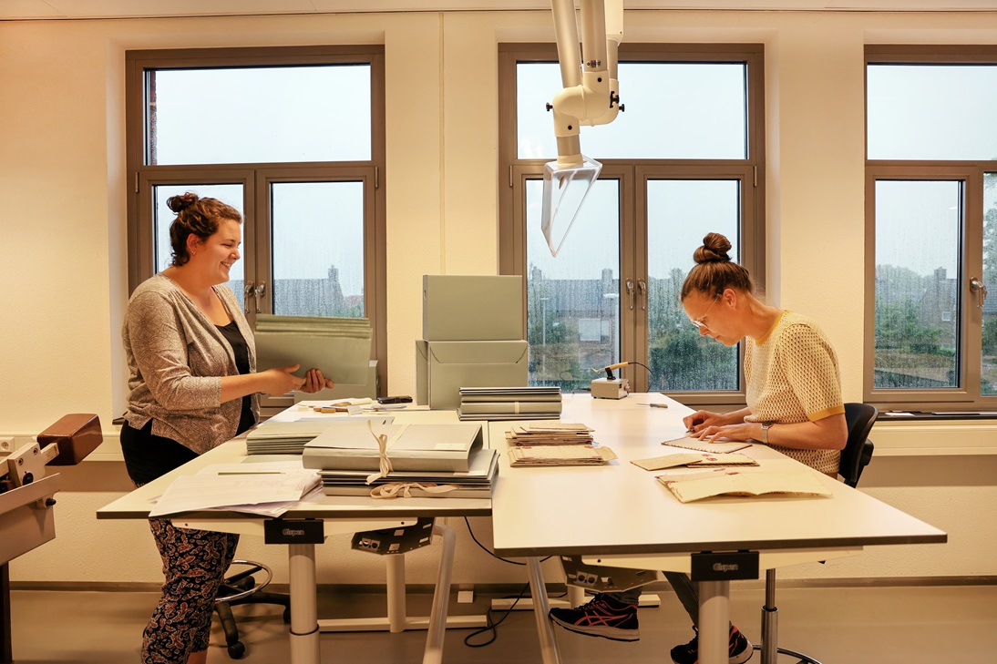 2 vrouwelijke medewerkers zijn bezig met het restaureren van oude stukken